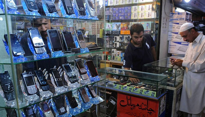 A shopkeeper can be seen showing mobile phones to a customer. — APP/File