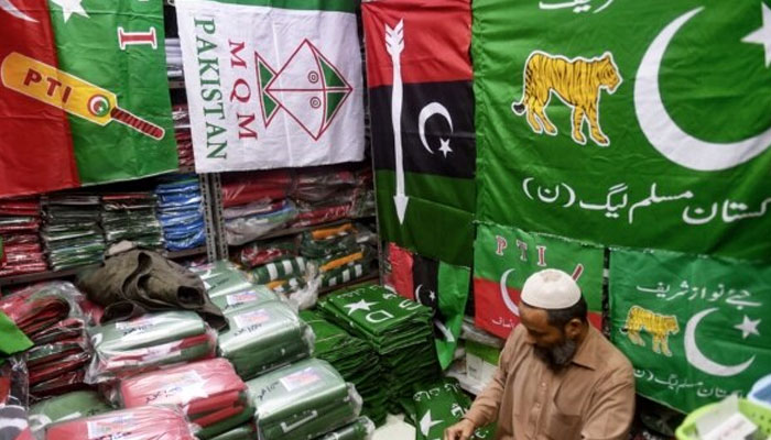 A shopkeeper arranges flags of political parties at his shop in Karachi. — AFP/File