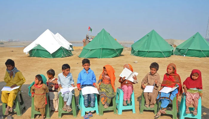 Children displaced due to floods attend a mobile school class near a makeshift camp. — AFP/File
