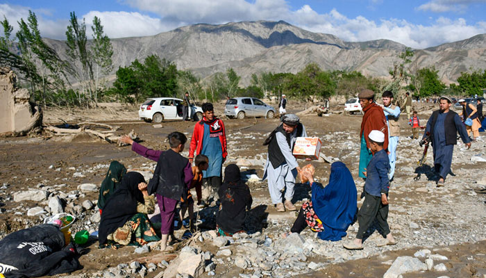 Afghans sit near damaged houses after floods in Burka district of Baghlan province on May 12, 2024. — AFP
