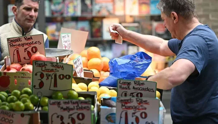 A customer pays for fruits at a stall in London. — AFP/File
