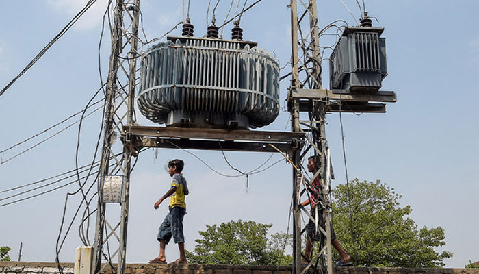 Two boys walk on a wall near high voltage electricity wires in Rawalpindi.—AFP/File