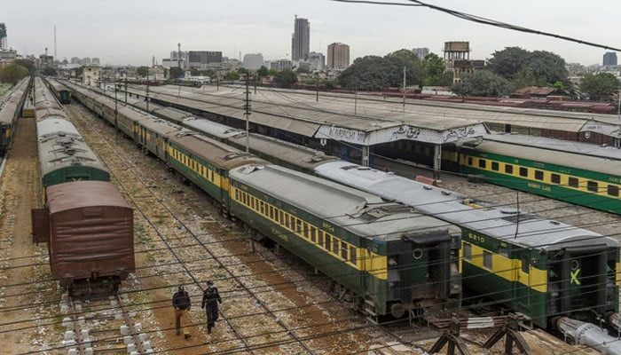 Policemen walk along trains at Karachi Cantonment railway station. — AFP/File