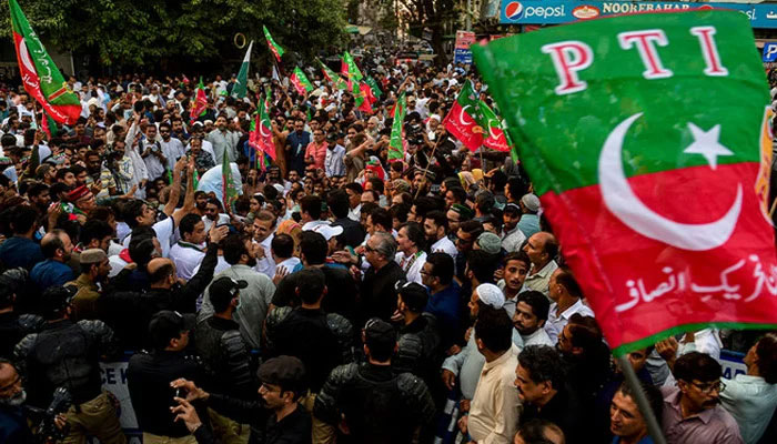 Supporters of PTI wave flags in a rally. — AFP
