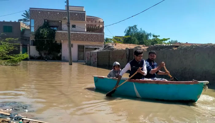 Residents row a boat to cross a flooded street after heavy rains in Gwadar in Balochistan province — AFP/file