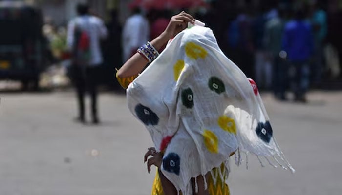A woman covers her child with a scarf to protect them from the heat on a road during a hot summer day in Bhubaneswar, India, May 3, 2024. — Reuters