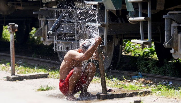A porter bathes at the railway station on a hot summer day in Lahore on May 30, 2024. — AFP