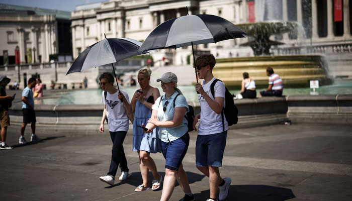 People carry umbrellas to hide in their shadow during a heatwave, at Trafalgar Square in London, Britain, July 19, 2022. — Reuters