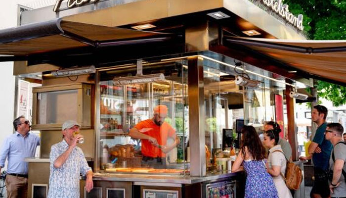 Customers queue outside the Wuerstelstand sausage stand near the famous Kaertner Street in Vienna, Austria on June 18, 2024. — AFP