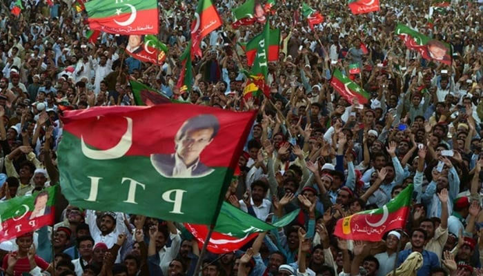 A crowd of PTI supporters wave the partys flag during a public gathering in Charsadda. — AFP/File