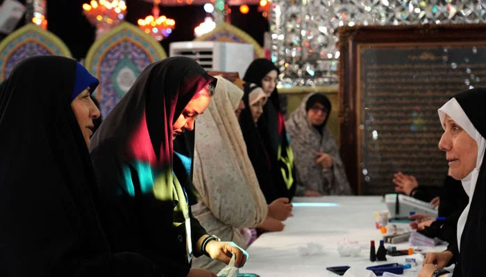 An Iranian woman arrives to cast her vote at a polling station in Tehran on July 5, 2024. — AFP