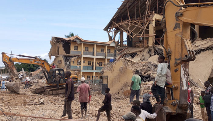 Bystanders gather next to heavy machinery working at the site of a school collapsed earlier in Jos, on July 12, 2024. — AFP