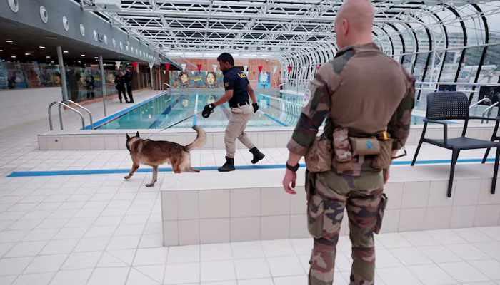 A police officer and a sniffer dog inspect a swimming pool area ahead of the Olympics on July 21, 2024. —  Reuters