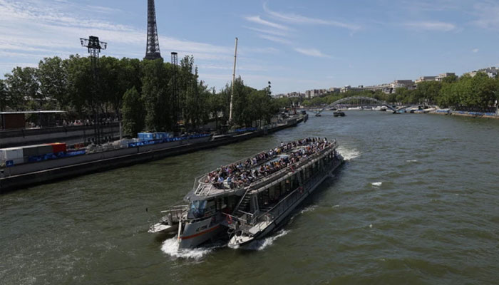 A tourist boat is navigated on the Seine river with Eiffel Tower in background, after the first triathlon training session was cancelled during the Paris 2024 Olympic Games in Paris, on July 28, 2024, due to the pollution of the Seine river.— AFP