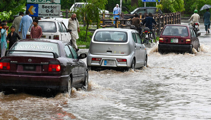 Commuters drive across a flooded street after heavy monsoon rains in Islamabad on July 10, 2024. — AFP