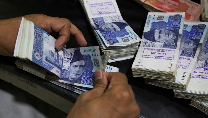 An employee counts Pakistani rupee notes at a bank in Peshawar on August 22, 2023. — Reuters