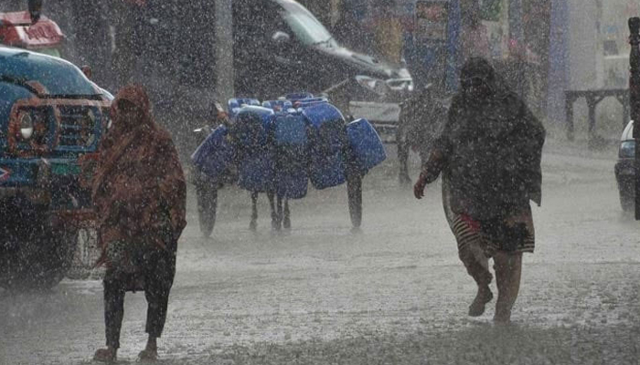 Women walk amid heavy rainfal on a street in Pakistan. — AFP/File