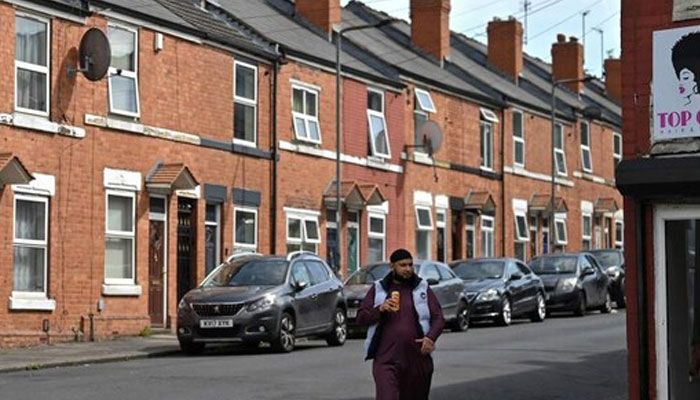 A person walks along on the footpath by a row of houses in the Eastwood area of Rotherham, northern England on August 13, 2024. — AFP