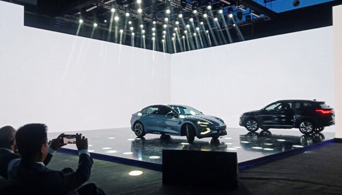 An attendee takes photos of Chinese electric vehicle BYD models on display in Lahore on August 17, 2024. — Reuters