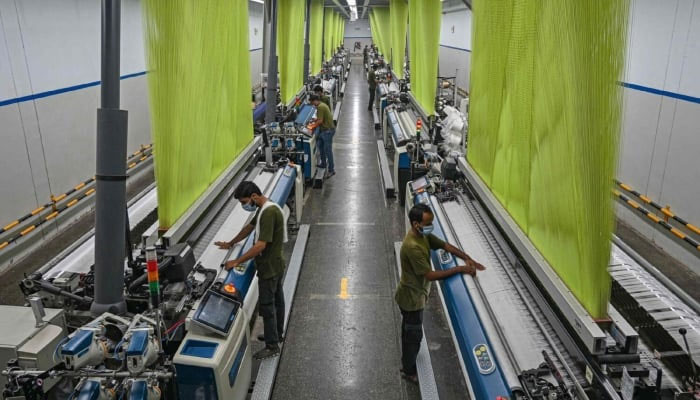 Representational image shows a worker operating a machine to prepare fabric at a textile mill in Lahore on July 20, 2023. — AFP