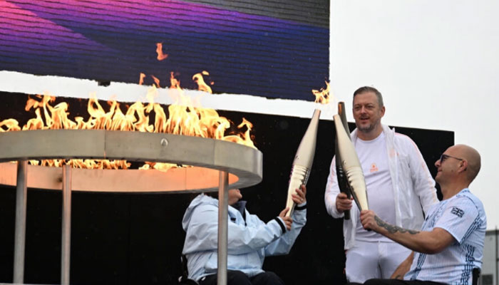 British Paralympic athletes Gregor Ewan and Helen Raynsford battled pouring rain to light the flame. — AFP