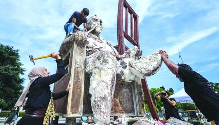 Syrian exiled sculptor Khaled Dawwa (top) with the help of relatives of people who disappeared in Syria, destroy his giant art work The King of Holes, depicting a potentate with a massive body, as part of a protest on the occasion of International Day of the Disappeared, in front of the United Nations offices in Geneva. – AFP/file