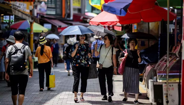 Three women holding umbrellas in a South Korean market in this image.— AFP/file