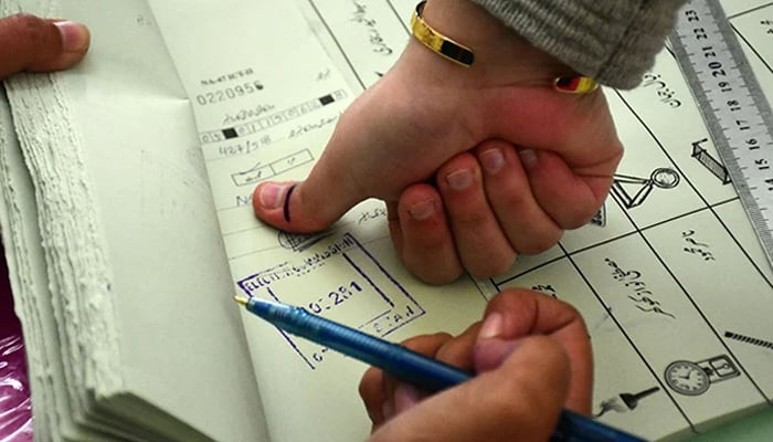 Man puts his thumb impression on ballot book prior to issuance of a ballot paper to cast vote at a polling station in Islamabad during general elections on February 8, 2024. — Online