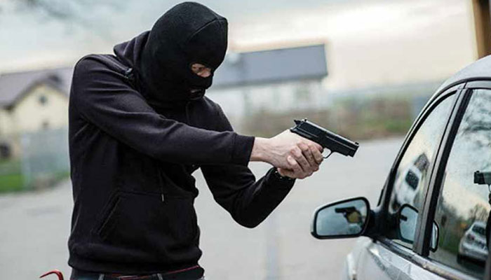 The representational image shows a robber with a gun aimed at a car. — Unsplash/File