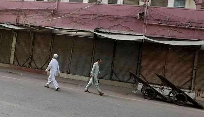 Representational image shows men walking along a closed market, during a shutter-down strike. — Reuters/File