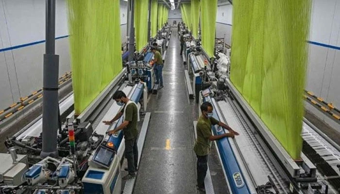 A worker operates a machine preparing fabric at the a textile mill in Lahore on July 20, 2023. — AFP
