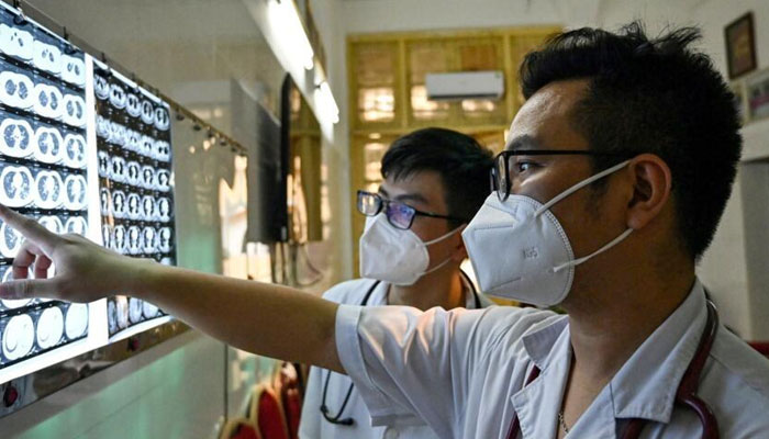 A Vietnamese doctor and his colleague check X-rays of a drug-resistant tuberculosis patient at the National Lung Hospital in Hanoi. — AFP/File