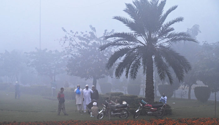 People walk around a park amid heavy smoggy conditions in Lahore on November 17, 2024. — AFP