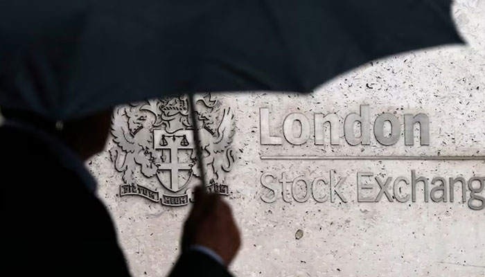 A man shelters under an umbrella as he walks past the London Stock Exchange in London, Britain August 24, 2015. — Reuters