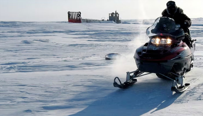 A Canadian part-time military volunteer drives over frozen sea past an abandoned landing craft off Cornwallis Island, Nunavut on April 9, 2006. —Reuters