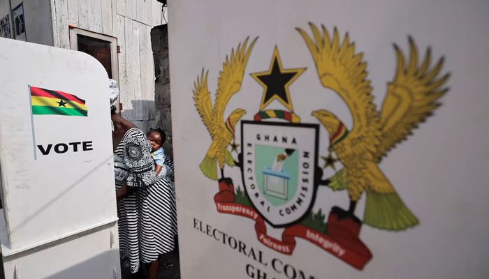 A woman carries a child as she votes at a polling station during the presidential and parliamentary election, near Jamestown, Accra, Ghana, December 7, 2024.— Reuters