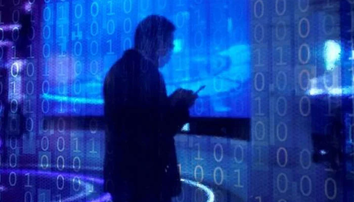 A man looking at a phone is seen through a digitally decorated glass. — Reuters/File