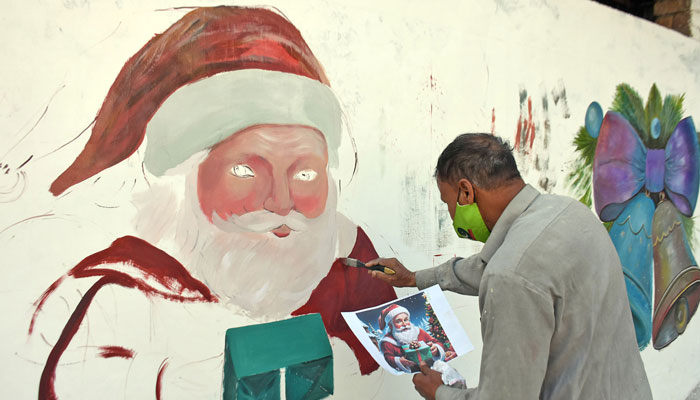 An artist paints Santa Claus on a wall alongside a road in connection with the upcoming Christmas, in Islamabad on December 16, 2024. — Online