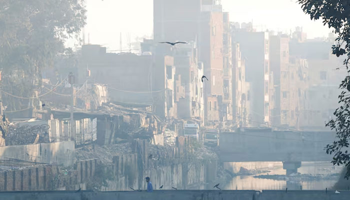 A man walks on a footbridge across an open drainage channel, as the sky is enveloped in smog caused by air pollution, in New Delhi, India, December 3, 2024. — Reuters