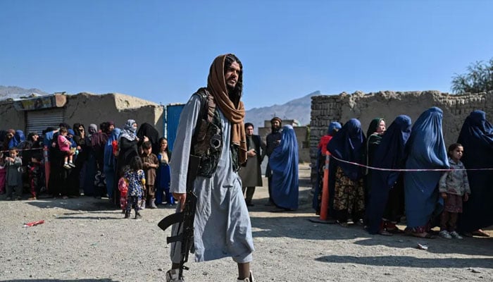 A Taliban soldier walking past veiled women.— AFP/File
