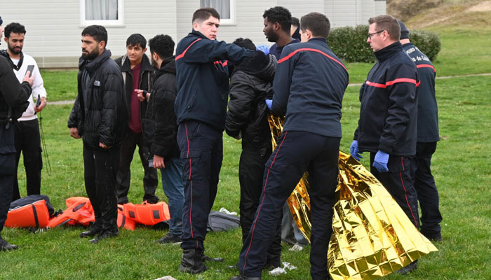 Firefighters help a migrant put on an emergency blanket after being rescued following a failed attempt to cross the English Channel to reach Britain, on the beach of Sangatte, northern France, on December 4, 2024. —AFP