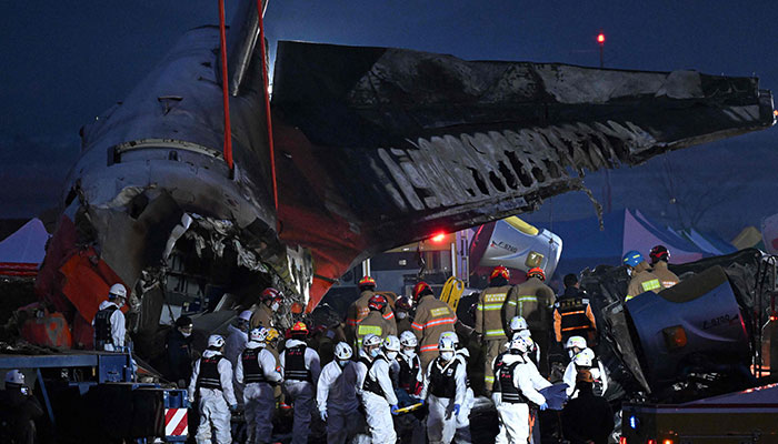 Firefighters and rescue personnel carry the body of a victim near the scene where a Jeju Air Boeing 737-800 series aircraft crashed at Muan International Airport in South Jeolla on December 29, 2024. —AFP
