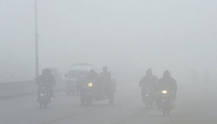 Motorists make their way along a street amid heavy fog. — AFP/File