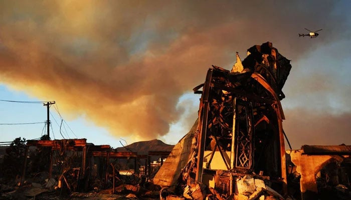 The Palisades Fire continues to burn above the remains of Community United Methodist Church, with a police helicopter flying past as wildfires cause damage and loss through Los Angeles County on January 10, 2025 in Pacific Palisades, California. — AFP