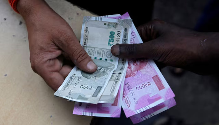 A customer hands Indian currency notes to an attendant at a fuel station in Mumbai, India, August 13, 2018.— Reuters