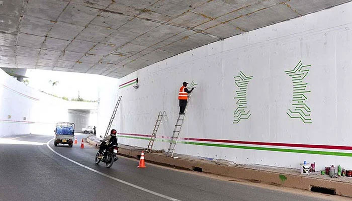A Painter busy making different designs on the wall of underpass. — APP/File