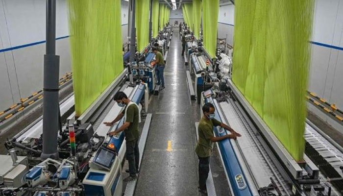Workers operate machines preparing fabric at the Kohinoor Textile Mills in Lahore on July 20, 2023. — AFP