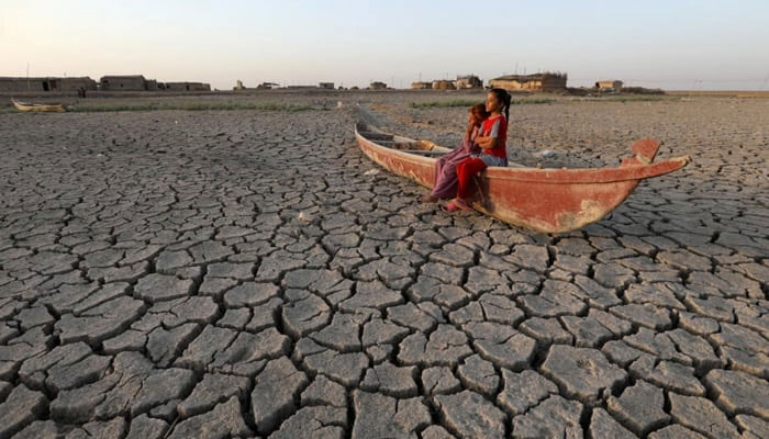 Children sit on a boat in the midst of a dry lake. — AFP/File