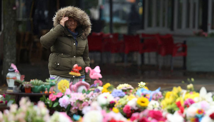 A woman seen walking past flowers in Southport, Britain, September 2, 2024. — Reuters