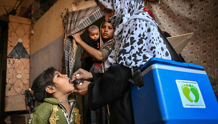 A health worker (R) administers polio drops to a child on the first day of a nationwide polio vaccination campaign, in Karachi on February 3, 2025. — AFP